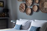 Schlichtes Boho-Schlafzimmer mit graublauer Wand und Wandtellern aus Bast