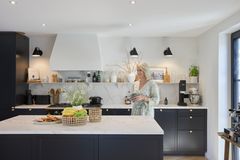 Frau in schwarzer Küche mit Arbeitsflächen aus Marmor