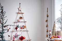 Selbst gebastelter Weihnachtsbaum aus unterschiedlich langen Ästen an der Wand hängend