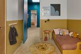 Kinderzimmer mit halbhoch gestrichener Wand in senfgelb und petrolblauer Tür