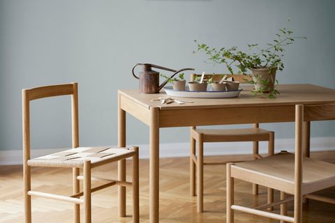 Esstisch mit Stuhlen aus hellem Holz vor hellblauer Wand