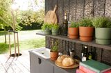 Regal mit Pflanzgefäßen in Outdoorküche an Hauswand