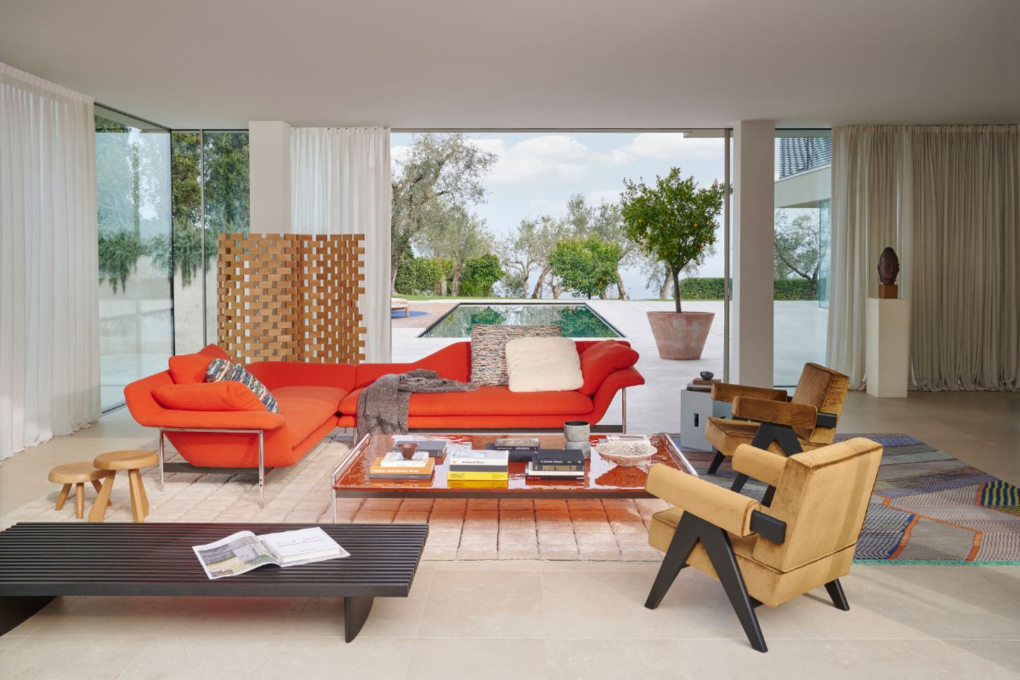 Wohnzimmer mit großer Fensterfront und leuchtend orangenem Sofa