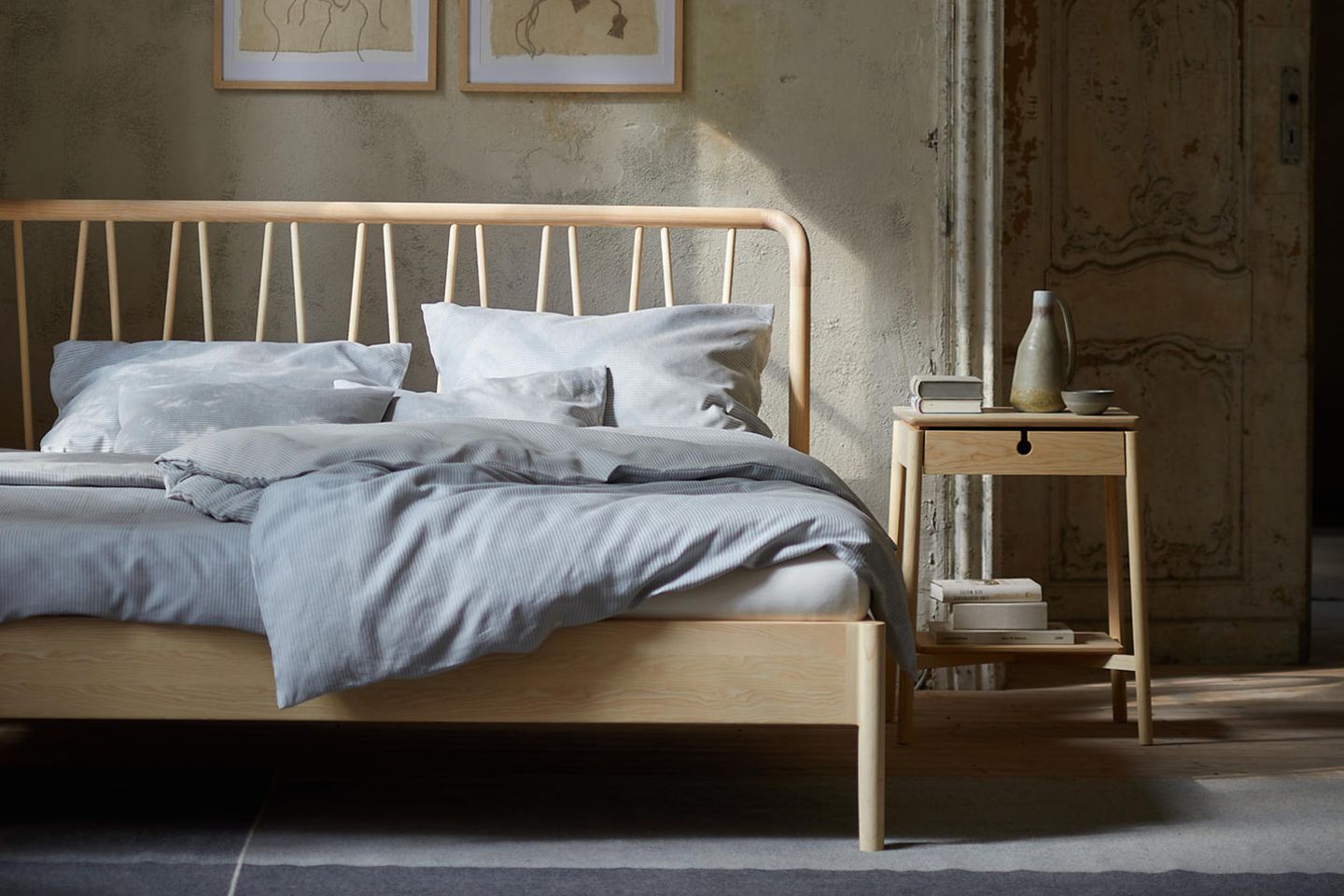 Bett mit dekorativem Holzheadboard steht vor einer Betonwand