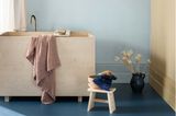 Badezimmer mit Waschtisch aus Holz und Wänden in Hellblau und Vanillegelb