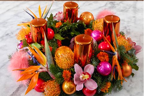 Tropisch anmutender Adventskranz mit kupferfarbenen Kerzen, Strelizien und Orchideenblüten