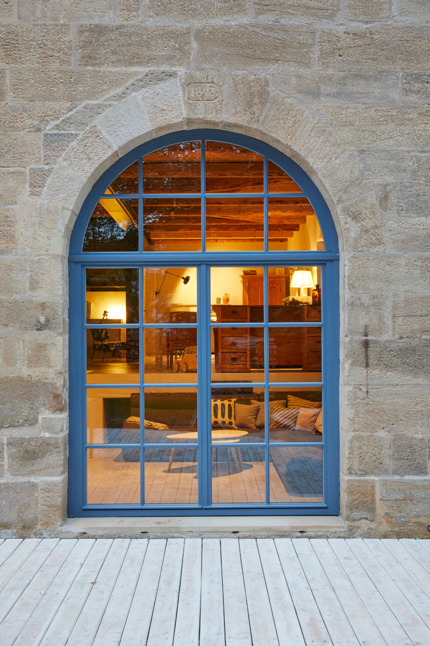 Historisches Rundbogentor mit Fenstereinsatz mit blauem Rahmen und Sprossen