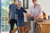 Familie in einem Wohnzimmer vor blauen Fensterrahmen