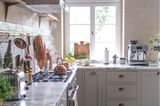 Blick auf ein Küchenfesnter in einer Landhausküche mit Arbeitsplatte aus Marmor und Gasherd.