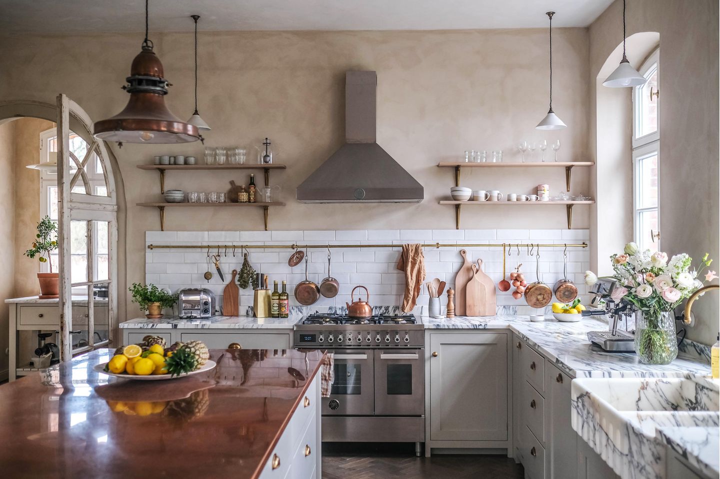 Landhausküche mit einem weißen Fliesenspiegel, Arbeitsplatten im Kupfer- und Marmor-Look und goldenen Akzenten aus Messing