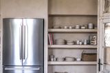 Kühlschrank und Regal in einer Küche mit Kalkfarbe an den Wänden.