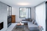 Wohnzimmer mit grauem Sofa und schwarze Metallwand als Raumtrenner