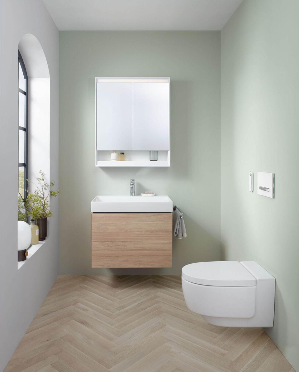 Gäste-WC mit hellgrünen Wänden und Möbeln in Weiß und Holz