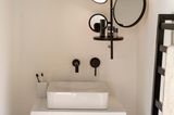 Beleuchtete Spiegelablage in einem Gäste-WC mit beigefarbener Wand und schwarzem Handtuchhalter