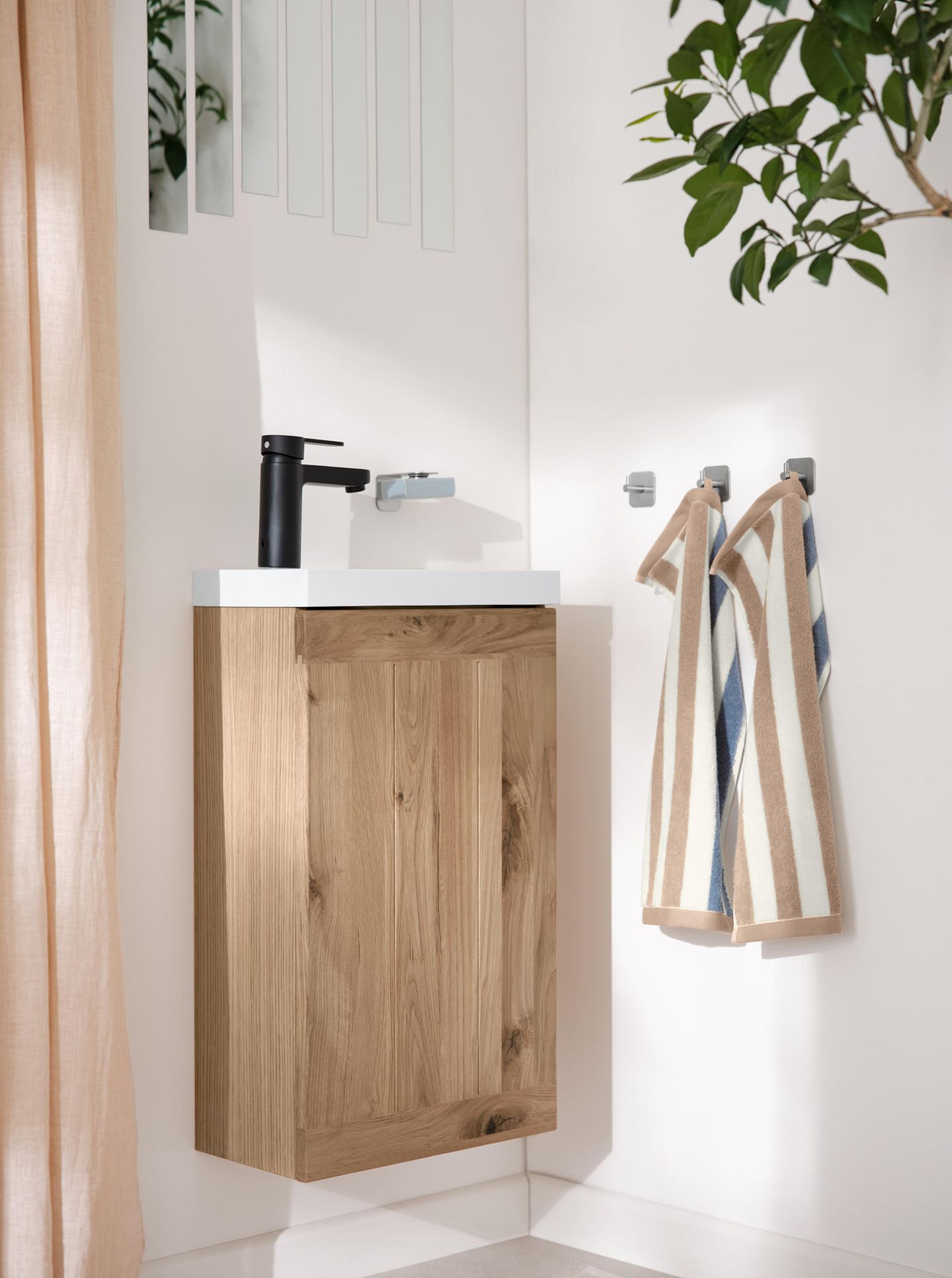 Waschbeckenunterschrank aus Holz und braun-gestreifte Handtücher in einem Gäste-WC