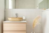Gäste-WC mit Waschbecken und WC und Wänden und Böden in hellem Creme und einem runden Juteteppich