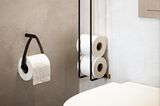 Toilettenpapierhalterung aus schwarzem Metall in einem kleinen Gäste-WC mit Betonwänden
