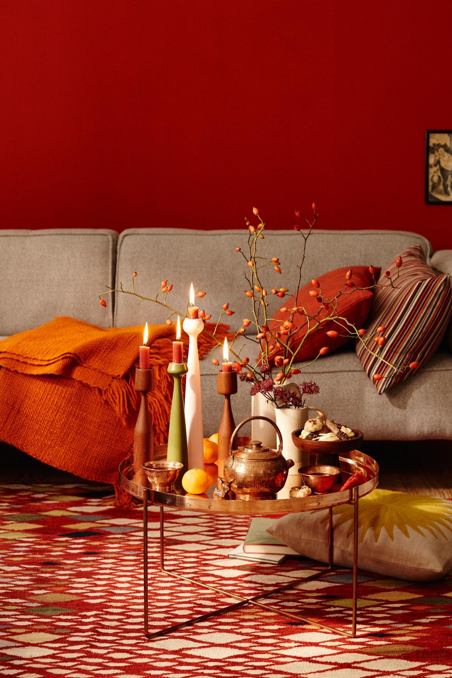 Rotes Wohnzimmer mit grauem Sofa und kleinem Couchtisch mit Kerzenständern