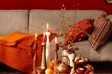 Rotes Wohnzimmer mit grauem Sofa und kleinem Couchtisch mit Kerzenständern
