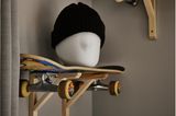 Wandkonsolen mit einem Skateboard als Ablage und einem Kopfmodell mit Mütze