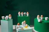 Zahlreiche Eierbecher von KPM Berlin auf vier unterschiedlichen Podesten in Grün und Türkis