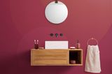 Badezimmerwand mit der "Viva Magenta"-Tapete von Hovia und einem hängendem Waschtisch plus Spiegel