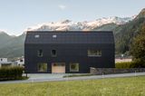 Schwarzes, freistehendes Haus mit Bergpanorama im Hintergrund