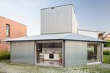 Futuristisches Haus mit großer Glasfront und silbernen Holzlamellen
