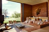Offenes Wohnzimmer mit deckenhoher Glasfront und Blick in die Landschaft