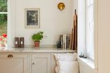 Banktruhe mit weißen Kissen in einer modernen Landhausküche mit grauen Fronten