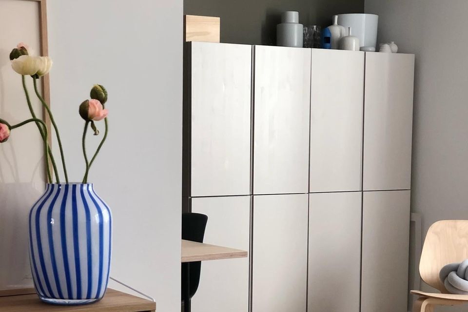 Schrank aus mehreren "Ivar"-Elementen von Ikea mit einer blauweiß gestreiften Vase und Ranukeln links im Vordergrund