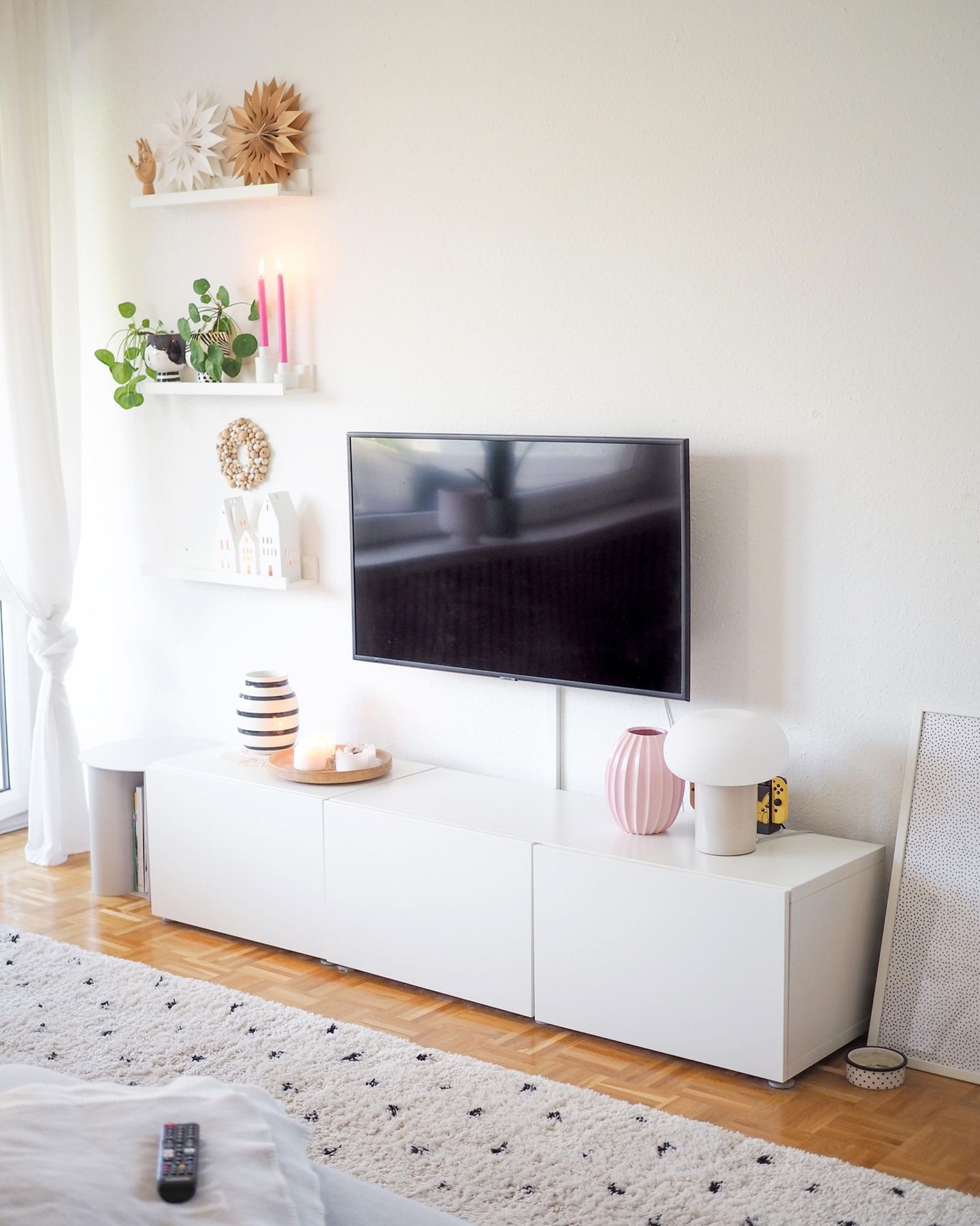 Langes weißes Sideboard als TV-Möbel mit Vasen und Deko auf einem Parkettboden