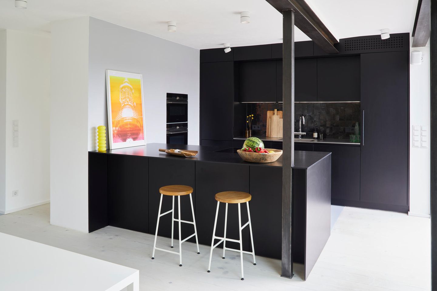 Schwarze Küche mit Stahlstrebe neben einer weißen Wand