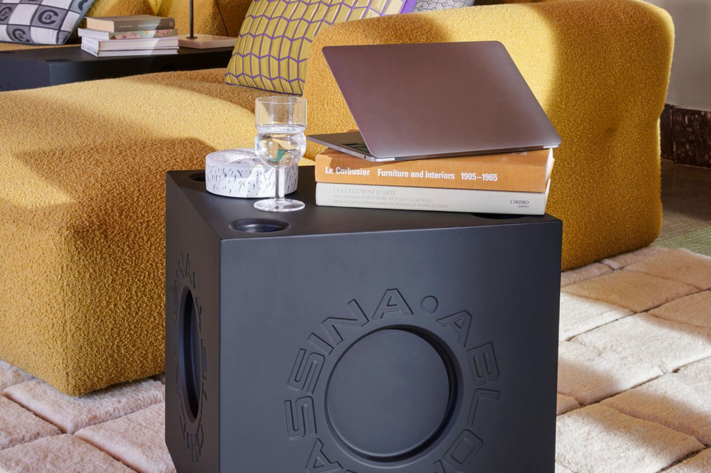 Schwarzes Wohn-Accessoire Modular Imagination von Cassina mit Glas und Laptop vor gelbem Sofa