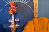 Wandbild auf einer blauen Wohnzimmerwand mit einer Vase und Sesseln