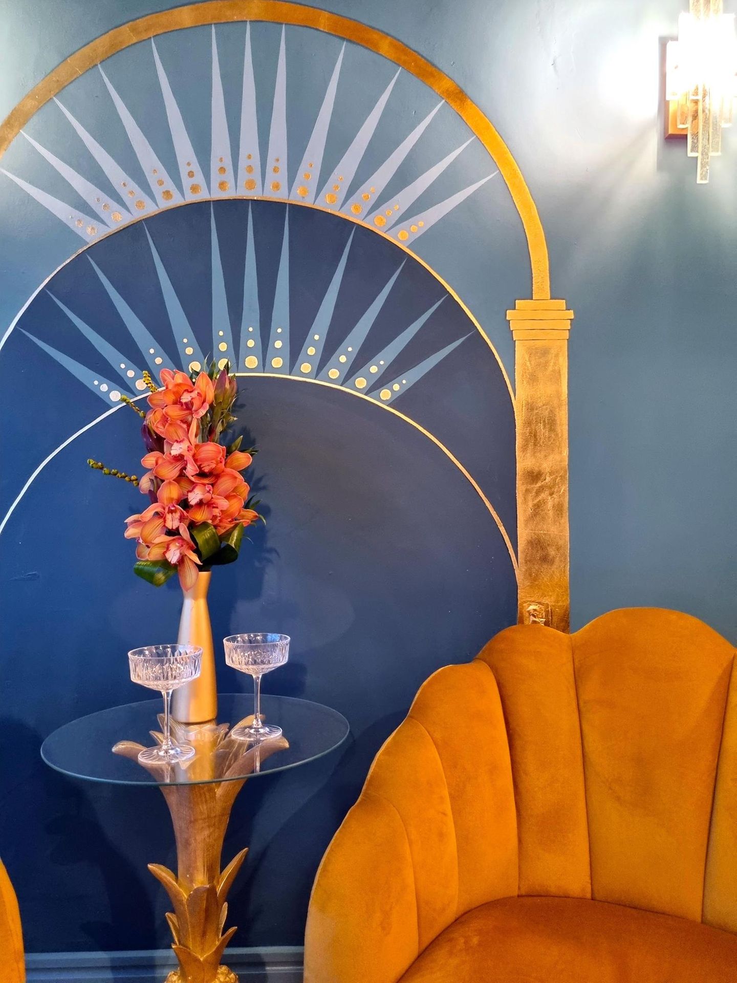 Wandbild auf einer blauen Wohnzimmerwand mit einer Vase und Sesseln