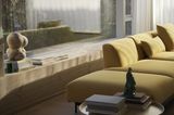 Senfgelbes Sofa vor breitem Sitzfenster mit Büchern auf der Fensterbank