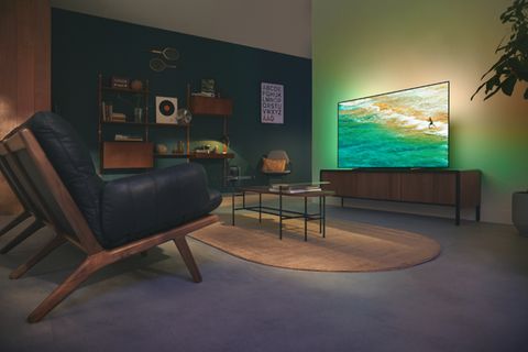 Wohnzimmer mit gepolsterter Ledersitzbank und einem Philips-Fernseher an der Wand