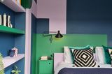Schlafzimmer mit Bett, Einbauregal und farbigen Wänden in Rosa, Grün und Blau