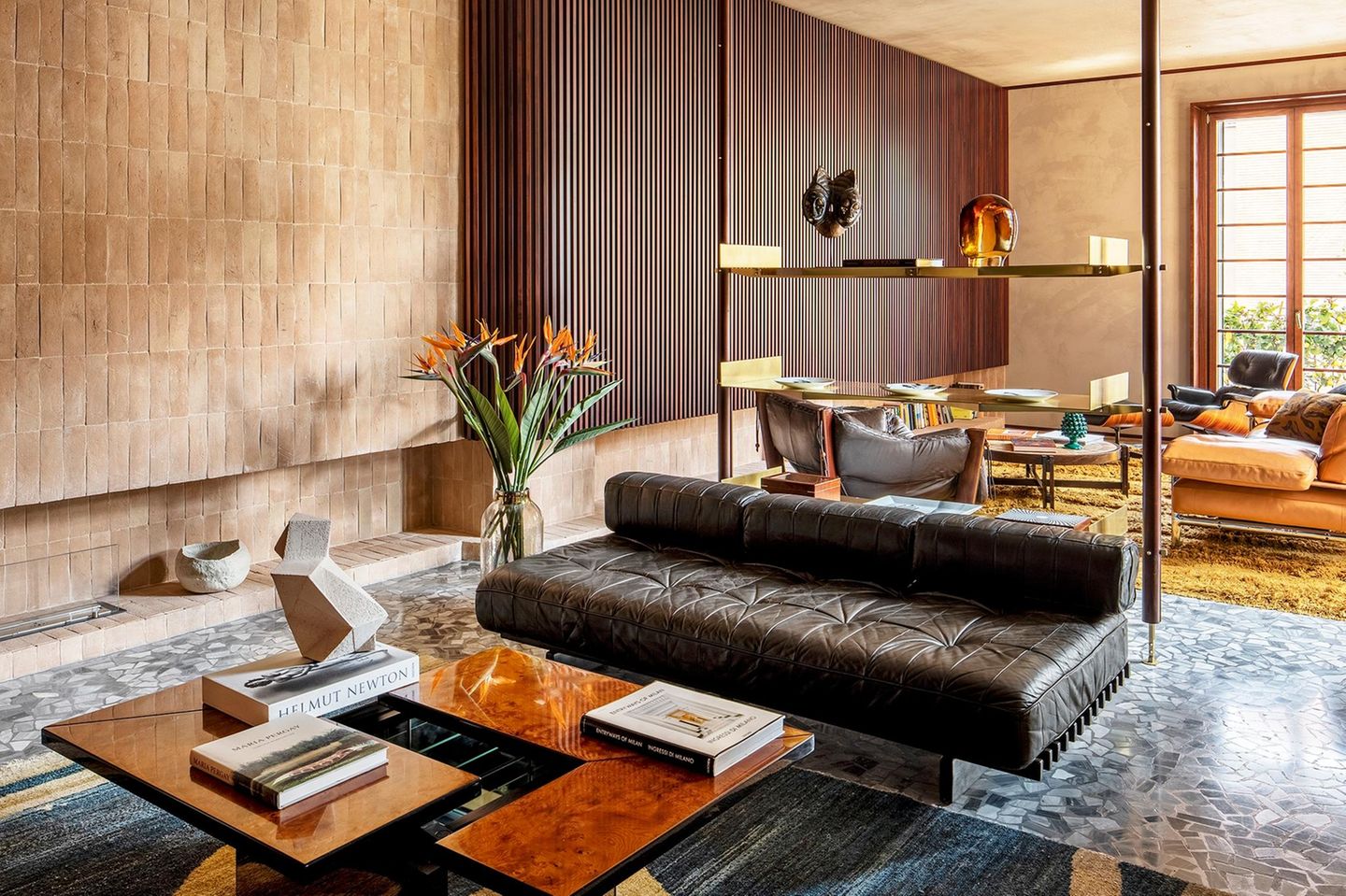 Regal als Raumteiler in einem Wohnzimmer mit braunen und schwarzen Sofas und Sesseln