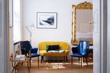 Ein Zimmer im Hotel Fregehaus in Leipzig mit gelbem Samtsofa und blauen Stühlen