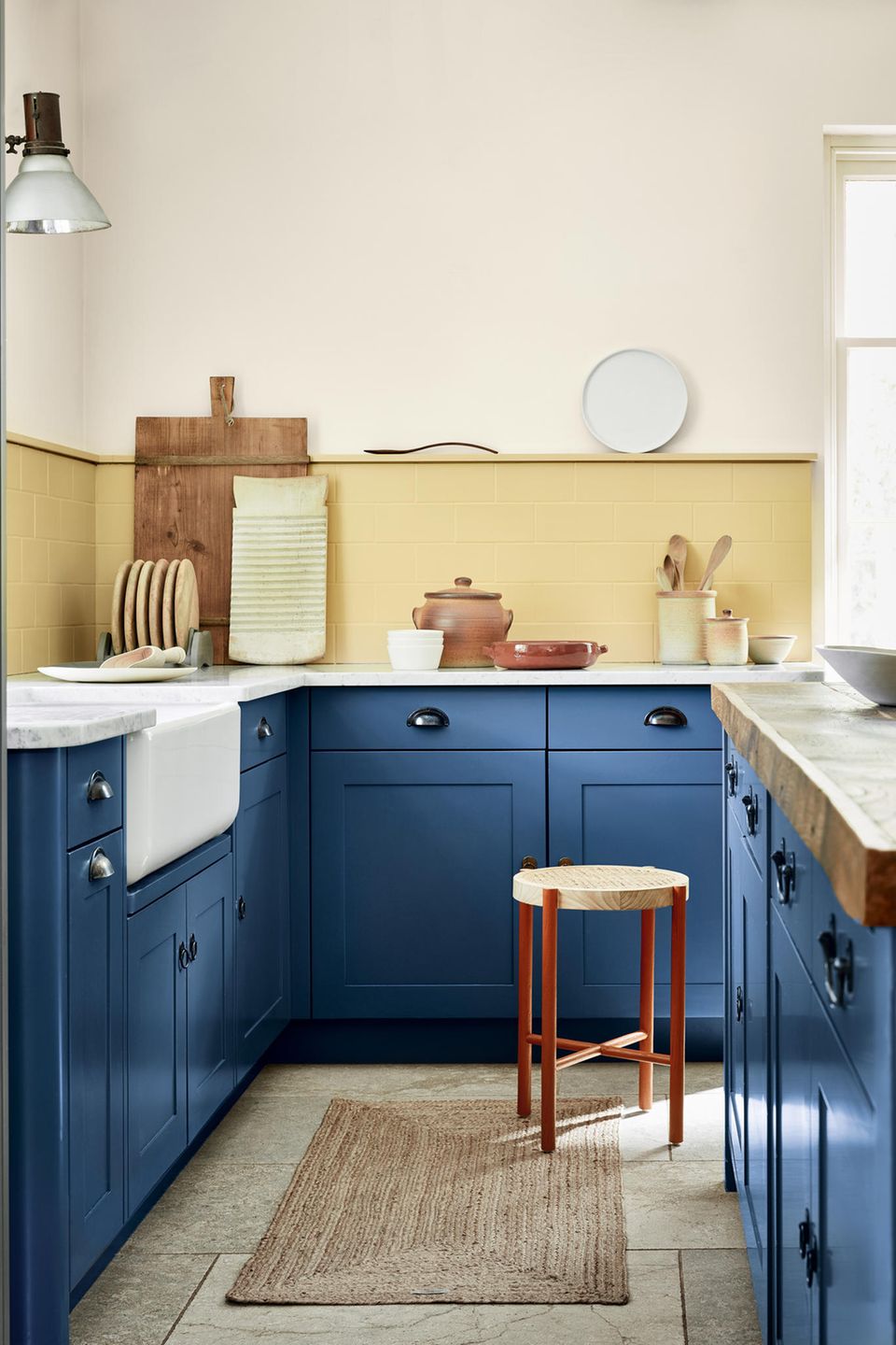 Schmale Küche mit dunkelblauen Fronten, beigem Wandpaneel und cremefarbenen Wänden