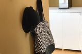 Schwarz lackierte Klebehaken als Geraderobe an einer ockerfarbenen Wand