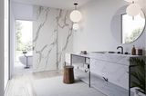 Helles Badezimmer mit freistehender Wanne im Hintergrund, Schiebetuer und Waschtisch aus Carrara Marmor im Vordergrund.