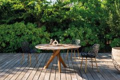 Tisch mit Natursteinplatte und Holzunterbau auf Holzterrasse und drei Stühlen