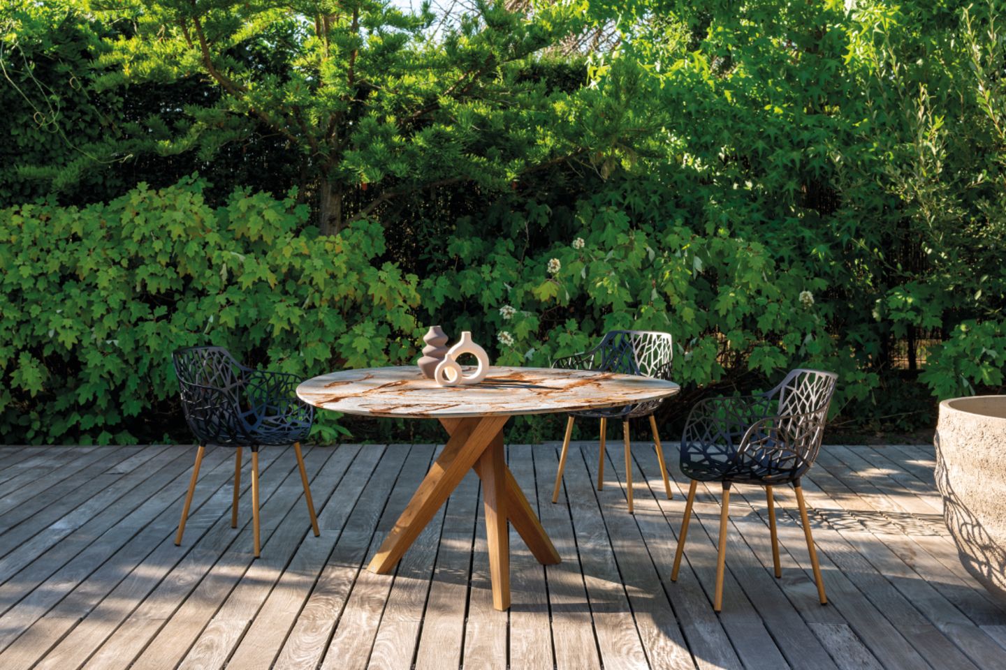 Tisch mit Natursteinplatte und Holzunterbau auf Holzterrasse und drei Stühlen