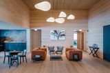 Hotellobby in Holz verkleidet mit orangenen Sofas und organischen Leuchten