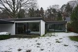 Blick auf einen Bungalow, im Garten liegt Schnee