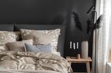 Dunkel gestaltetes Schlafzimmer mit Bettwäsche in Beige