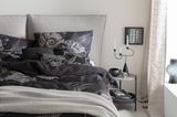Dunkle Bettwäsche mit floralem Muster im hellgrau gestalteten Schlafzimmer